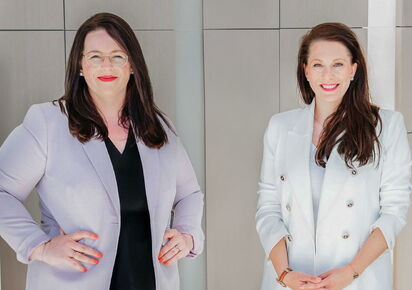 Geschäftsführerinnen der Grabowski & Rohmann Personalberatung Hamburg, zwei Frauen im hellgrauen und weißen Blazer stehen selbstbewusst in modernem Büroambiente